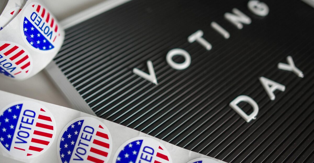 I Voted stickers with an American flag design and Voting Day sign symbolize U S electoral participation