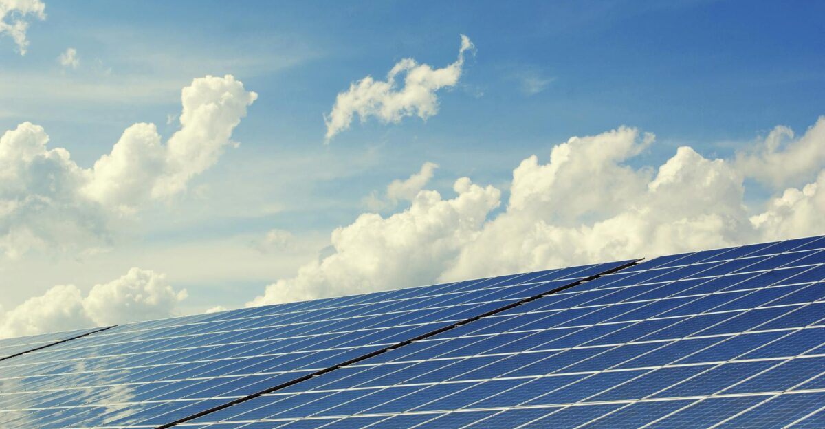 Sleek modern solar panels under a vibrant blue sky with clouds symbolizing clean energy