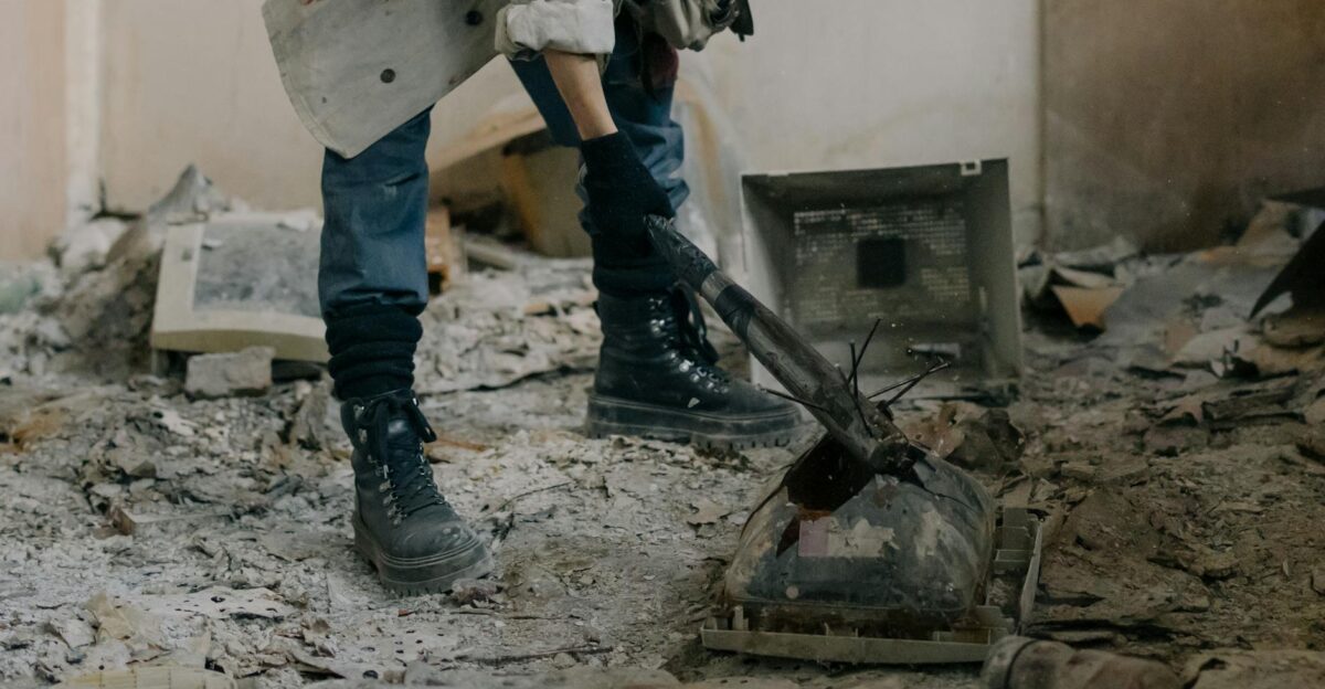 Rugged individual breaking outdated electronics in a derelict dusty interior