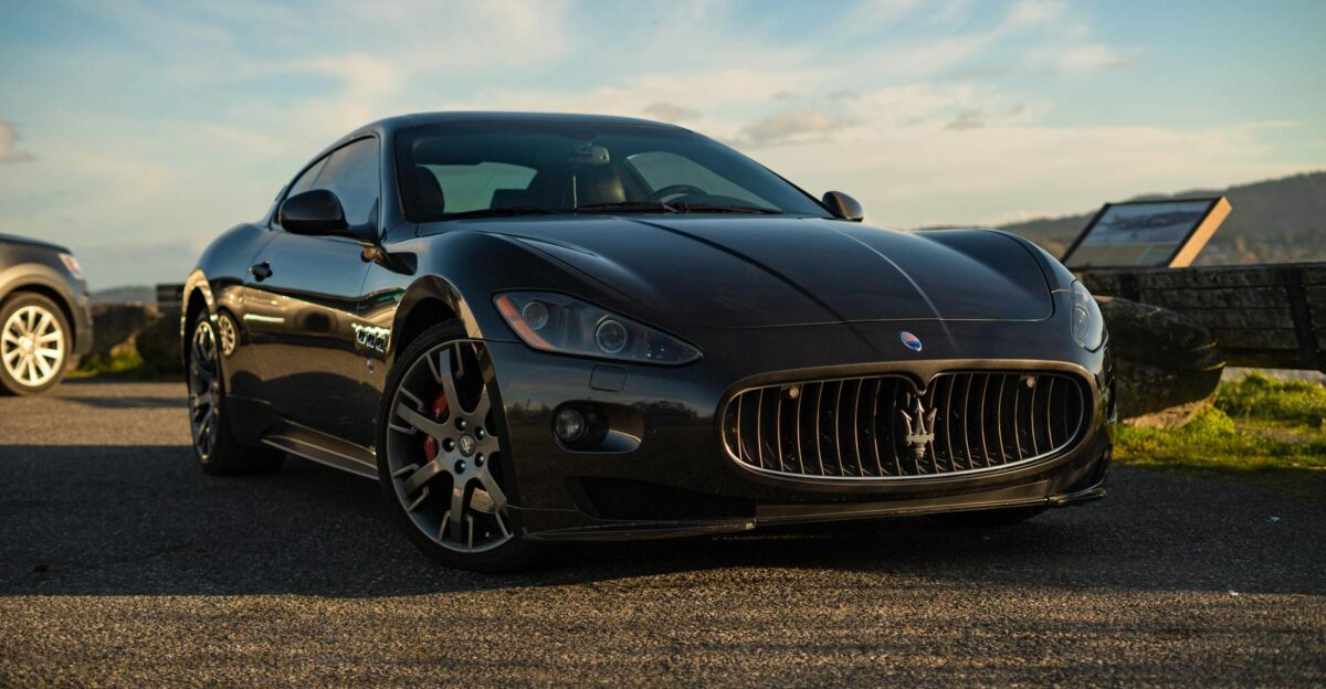 A sleek black Maserati sports car parked outdoors under a clear sky