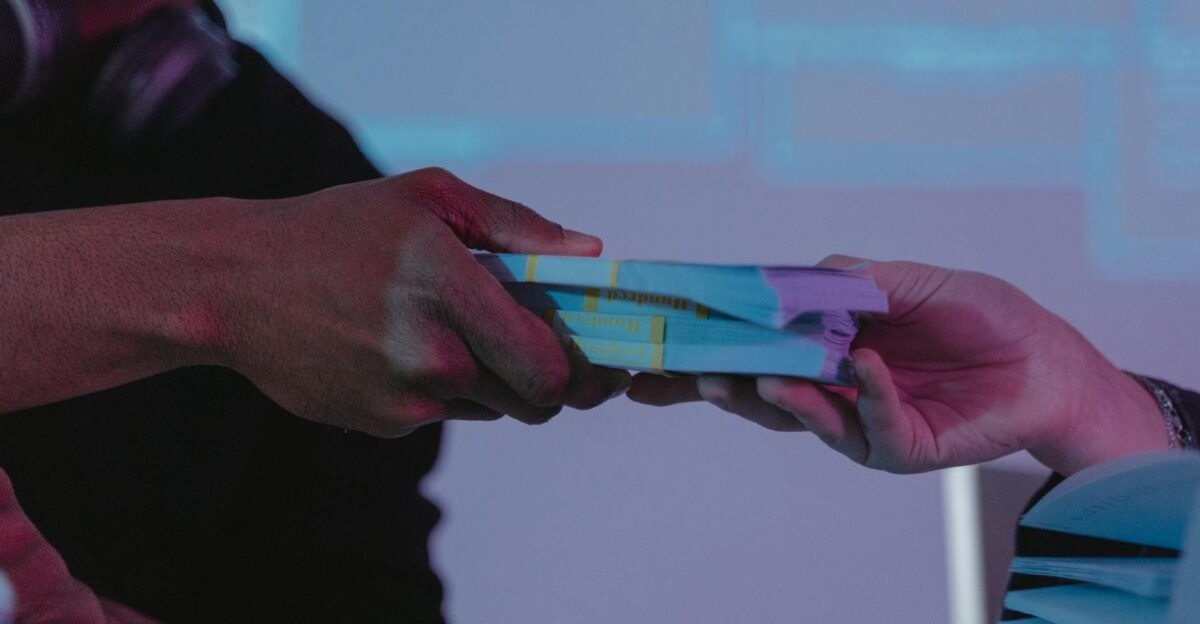 Close-up of hands exchanging money highlighting financial exchange in a dimly lit setting
