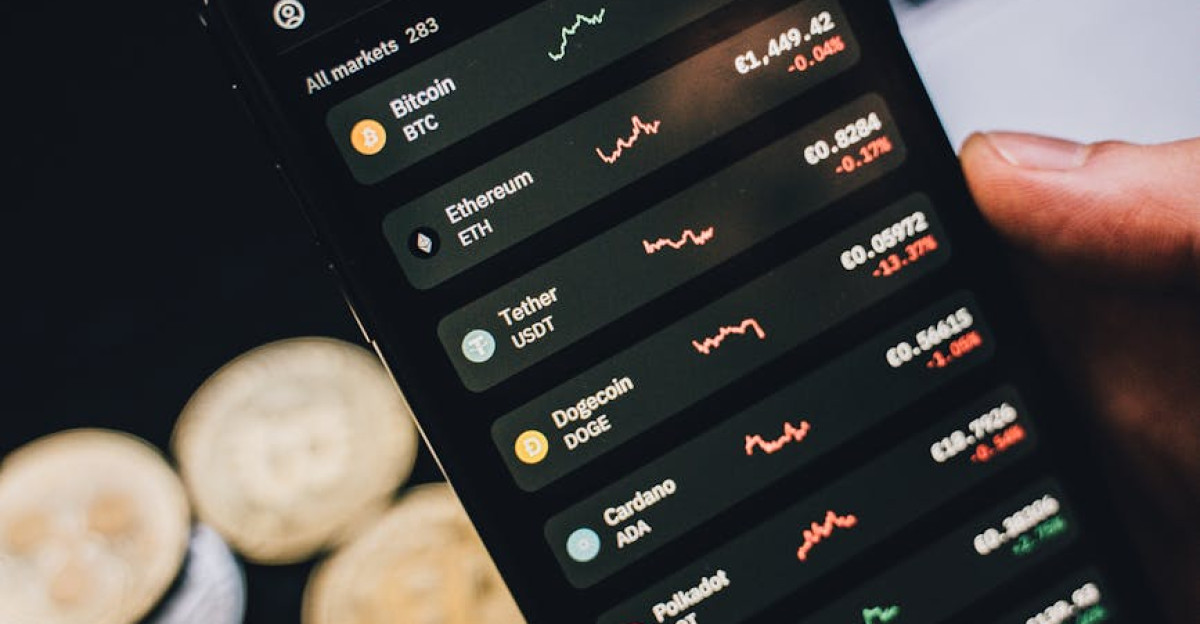 Close-up of a smartphone showing cryptocurrency trends with coins in the background