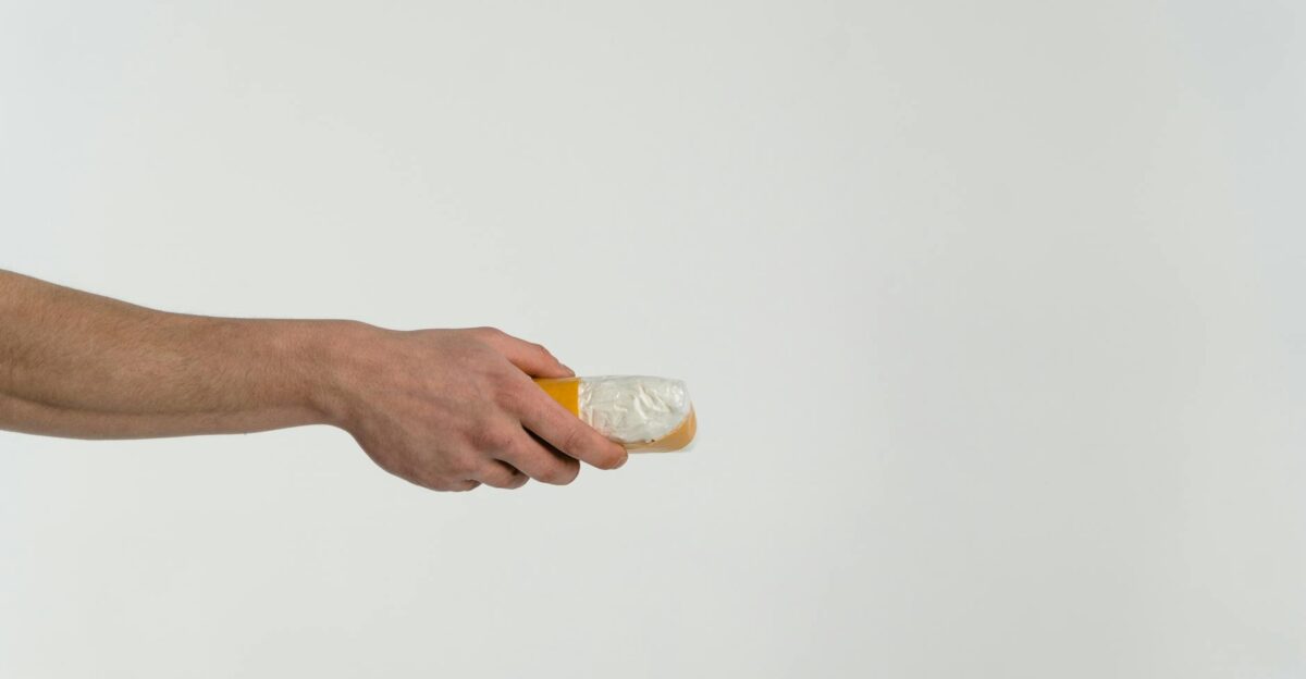 A hand holds a transparent bag containing a white substance against a neutral backdrop