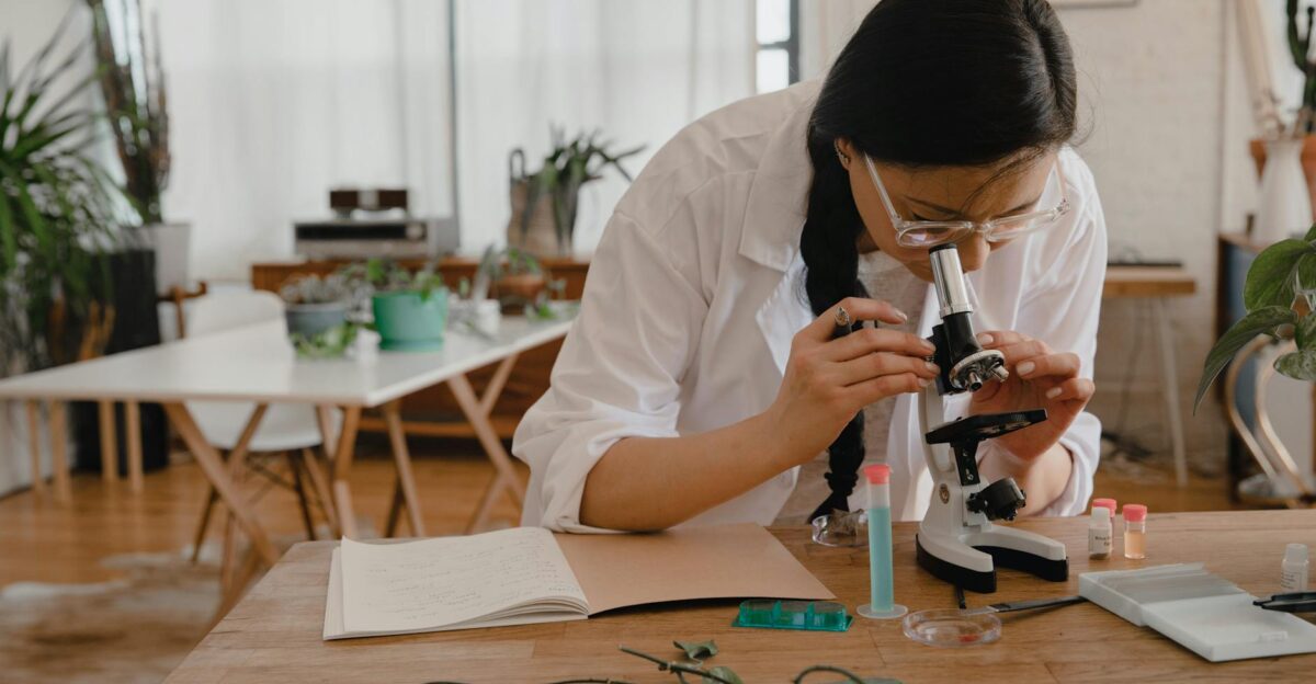 A scientist using a microscope to analyze samples in a modern indoor lab
