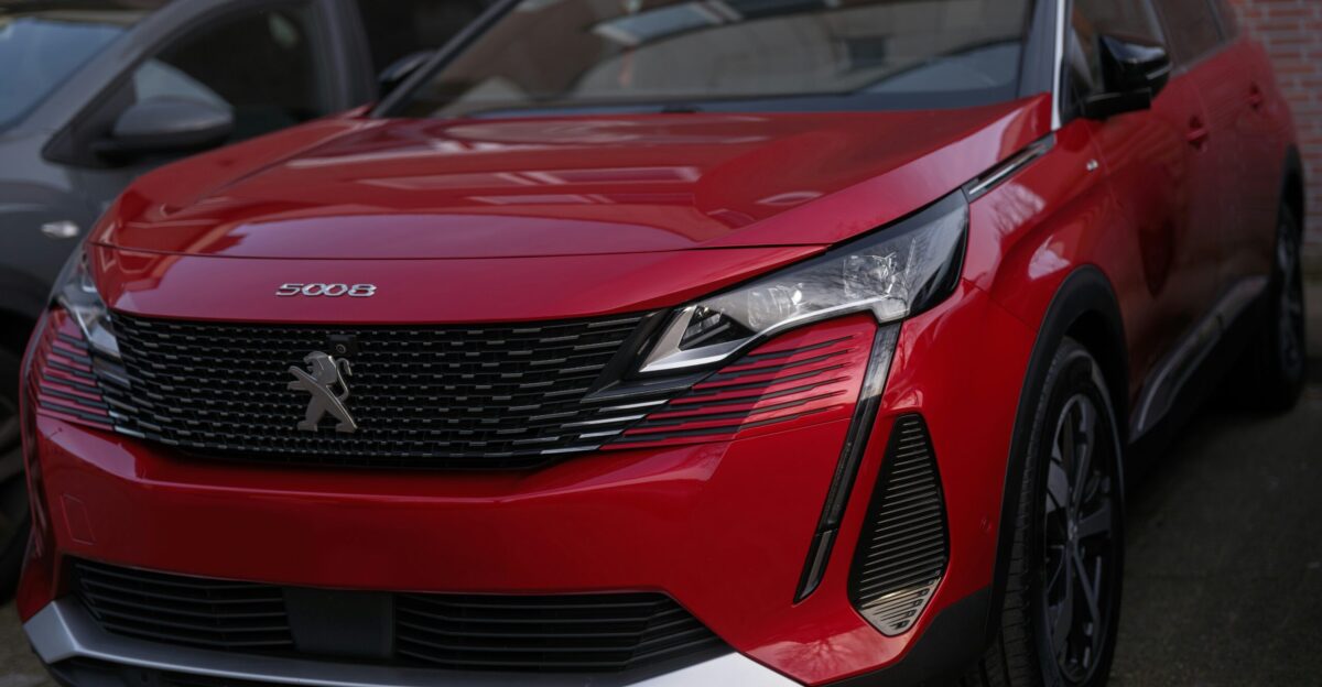 A red peugeot suv is parked outside
