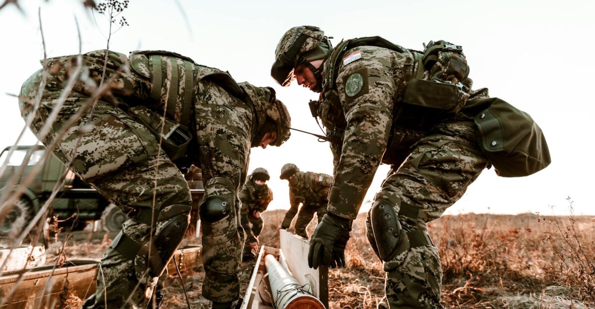 Soldiers in camouflage uniforms during training exercises at sunset in an open field