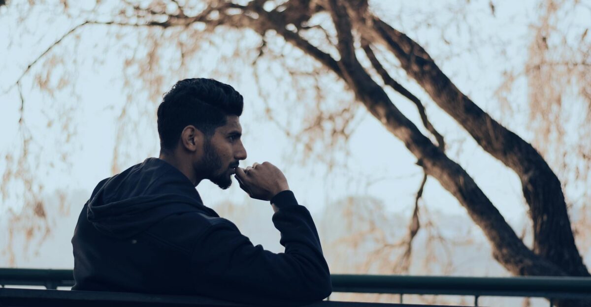 Man in deep thought sitting on a bench in a serene autumn park setting