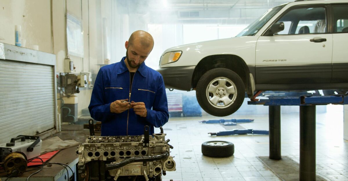 A mechanic in blue uniform inspecting an engine in a professional auto repair workshop