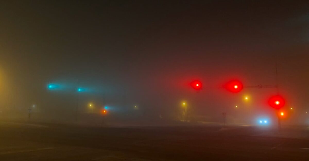 a foggy night with traffic lights and street signs