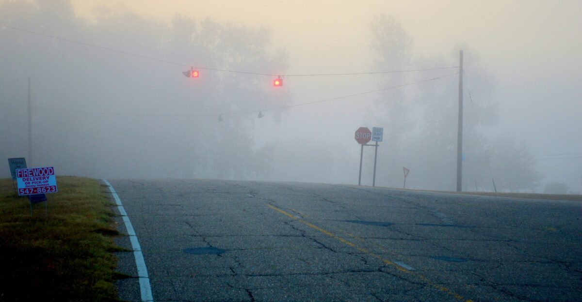 Traffic lights glowing through thick morning fog