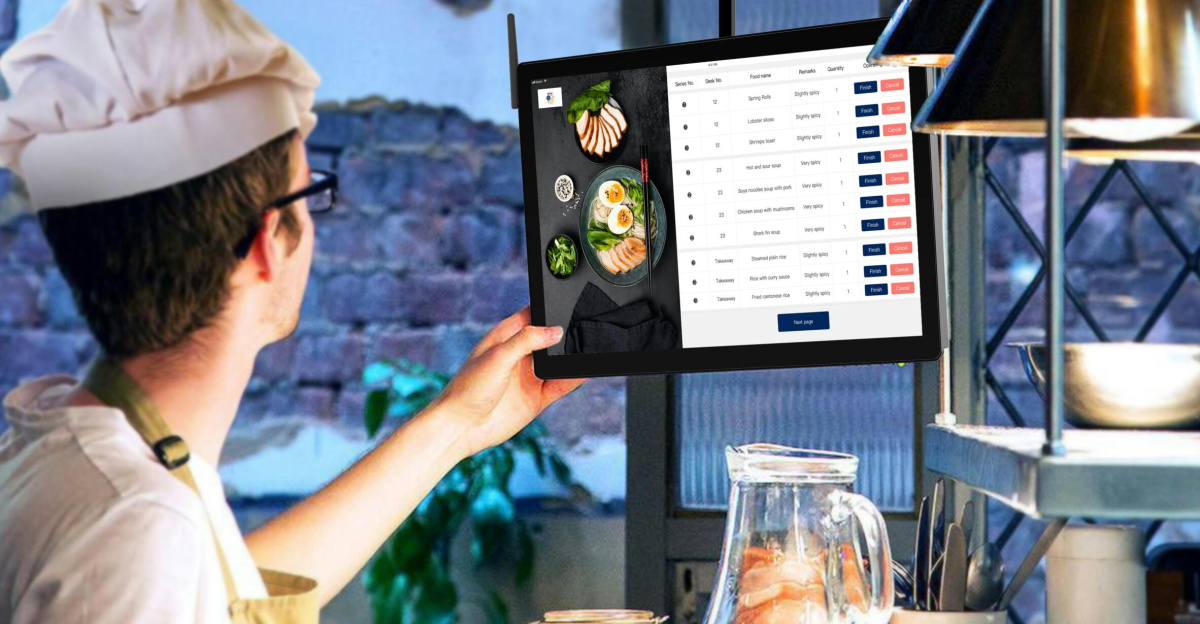 Chef using a tablet to manage kitchen orders in a restaurant setting.